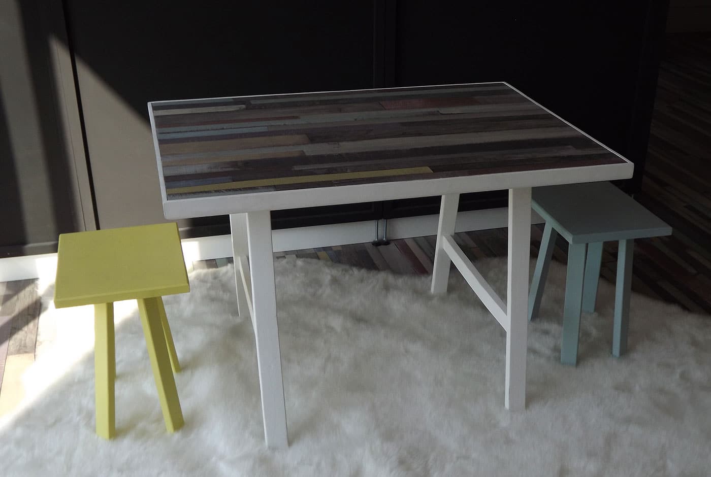 Table enfant avec 2 tabourets jaune et bleu. Cette table dispose d'un plan de travail en parquet stratifié.